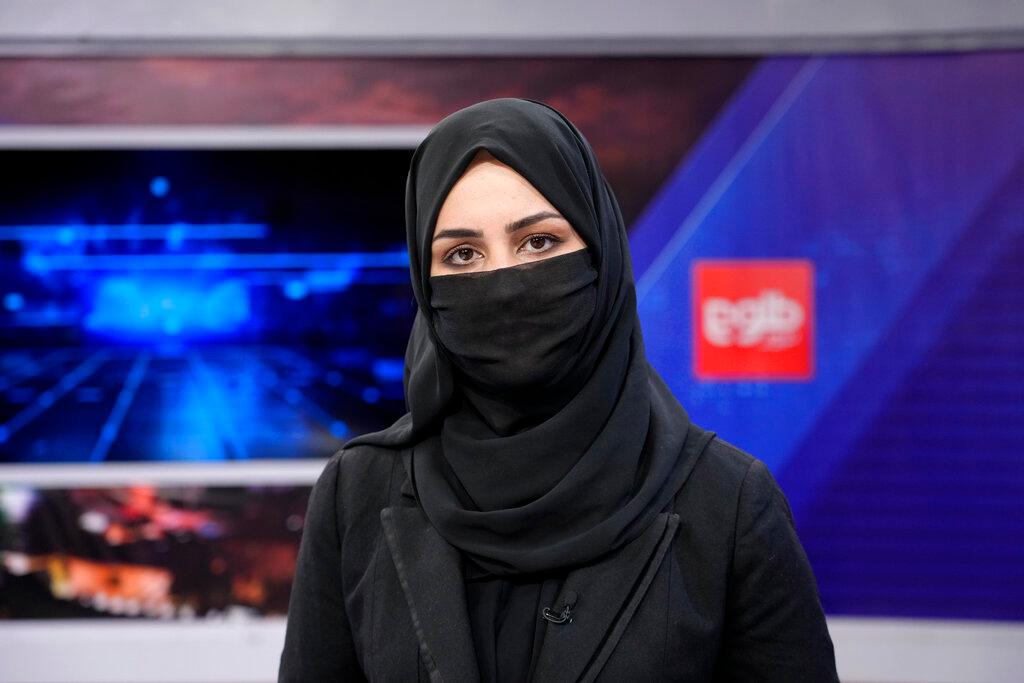 a TV anchor wears a face covering as she reads the news