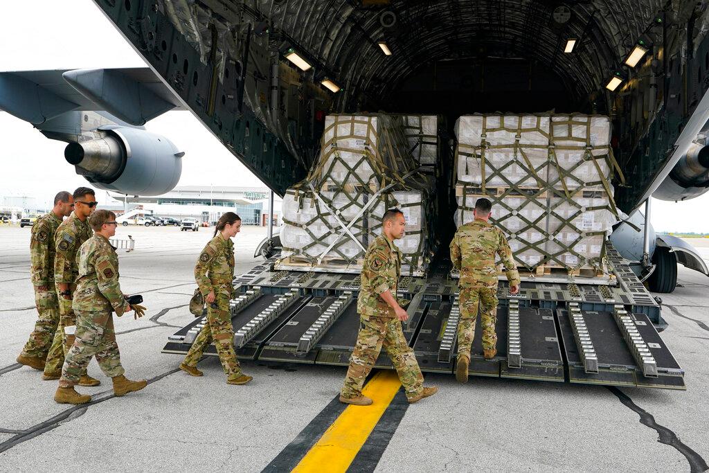 Crew members begins to unload a plane load of baby formula
