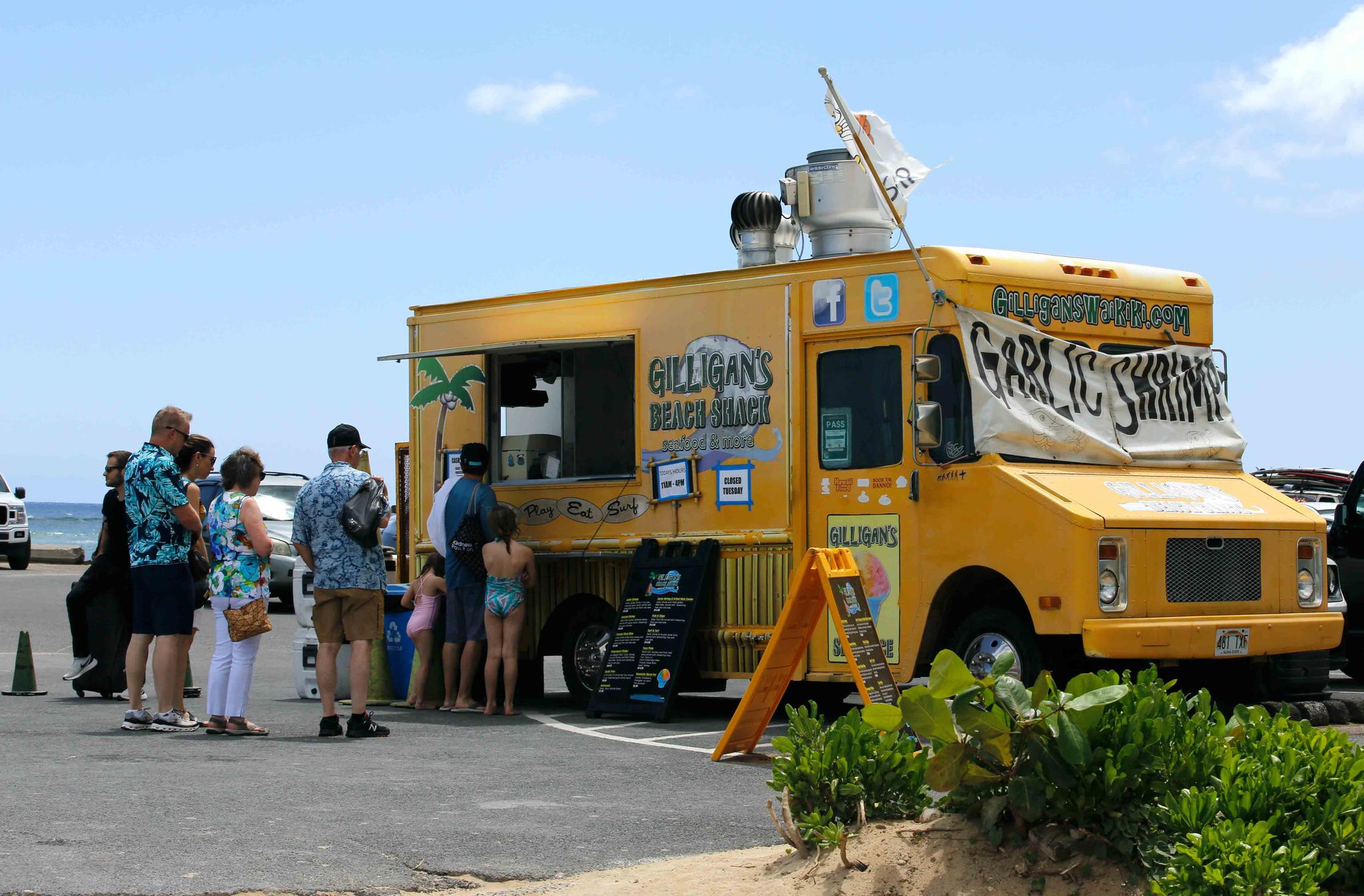 People line up at a food truck parked near Waikiki Beach in Honolulu, Monday, May 23, 2022. 