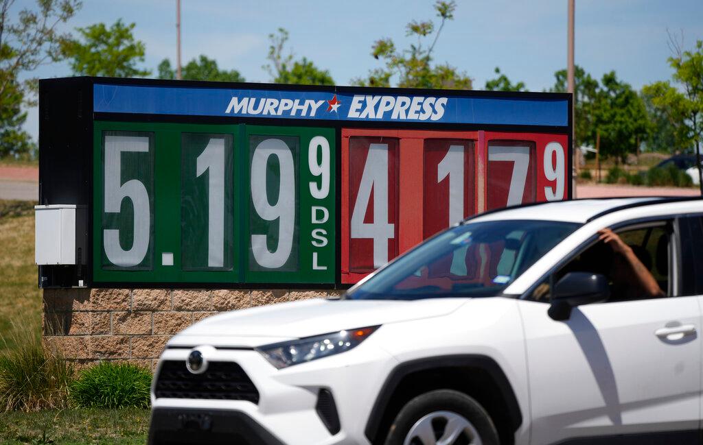 Gasoline prices are displayed outside a convenience store as a motorist drives by in Thornton, Colo.