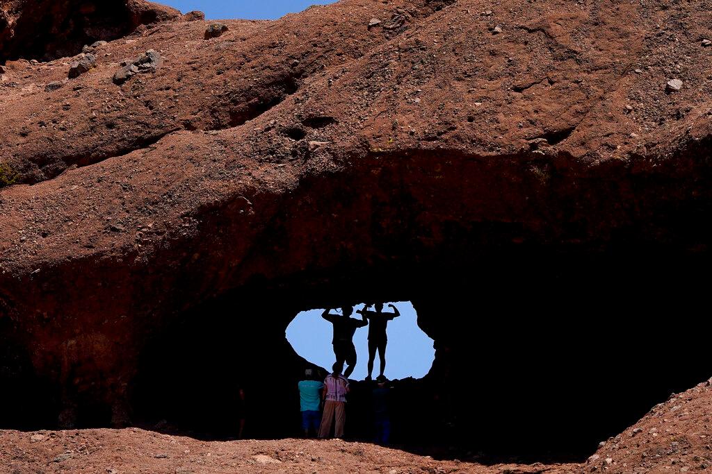 A pair of mid-day hikers pose for a picture in the hole in the rock at Papago Park, Friday, June 10, 2022, in Phoenix. Heat is part of the normal routine of summertime in the desert, but weather forecasters say that doesn't mean people should feel at ease. Excessive heat causes more deaths in the U.S. than other weather-related disasters, including hurricanes, floods and tornadoes combined. Officials are advising people to limit time outdoors, drink plenty of water and seek shade if they must be outside.