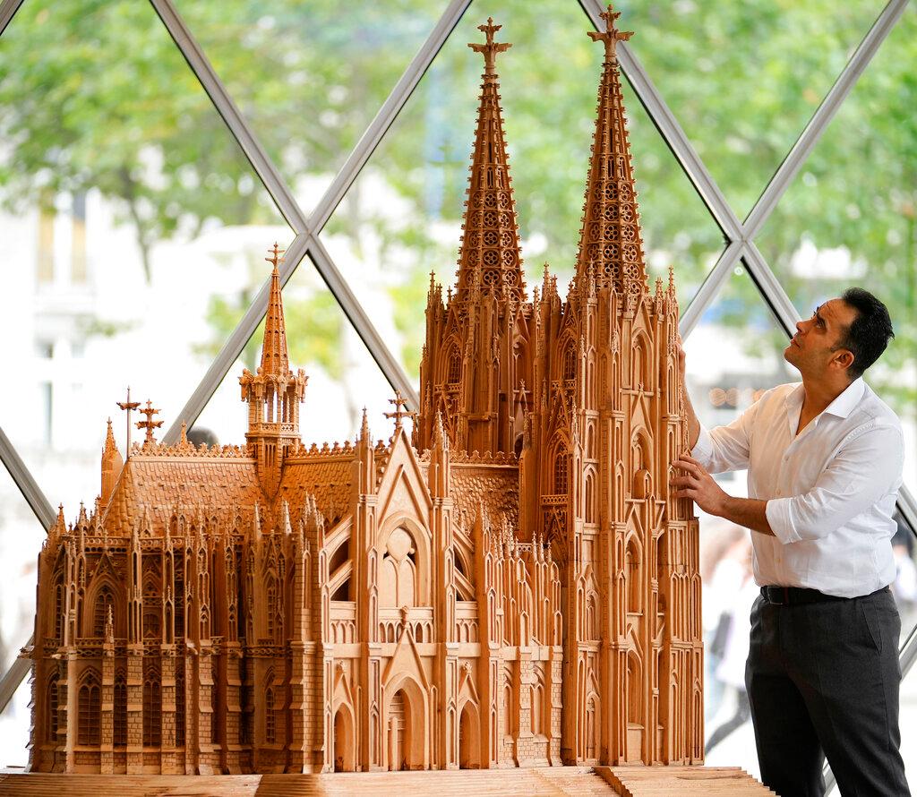 Fadel Alkhudr from Syria poses beside his wooden model of the word heritage Cologne Cathedral on display at the Domforum in Cologne, Germany