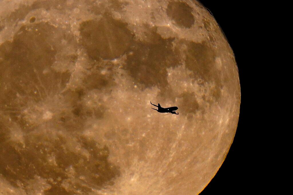 A plane passes in front of a full moon Wednesday, July 13, 2022, in Milwaukee.