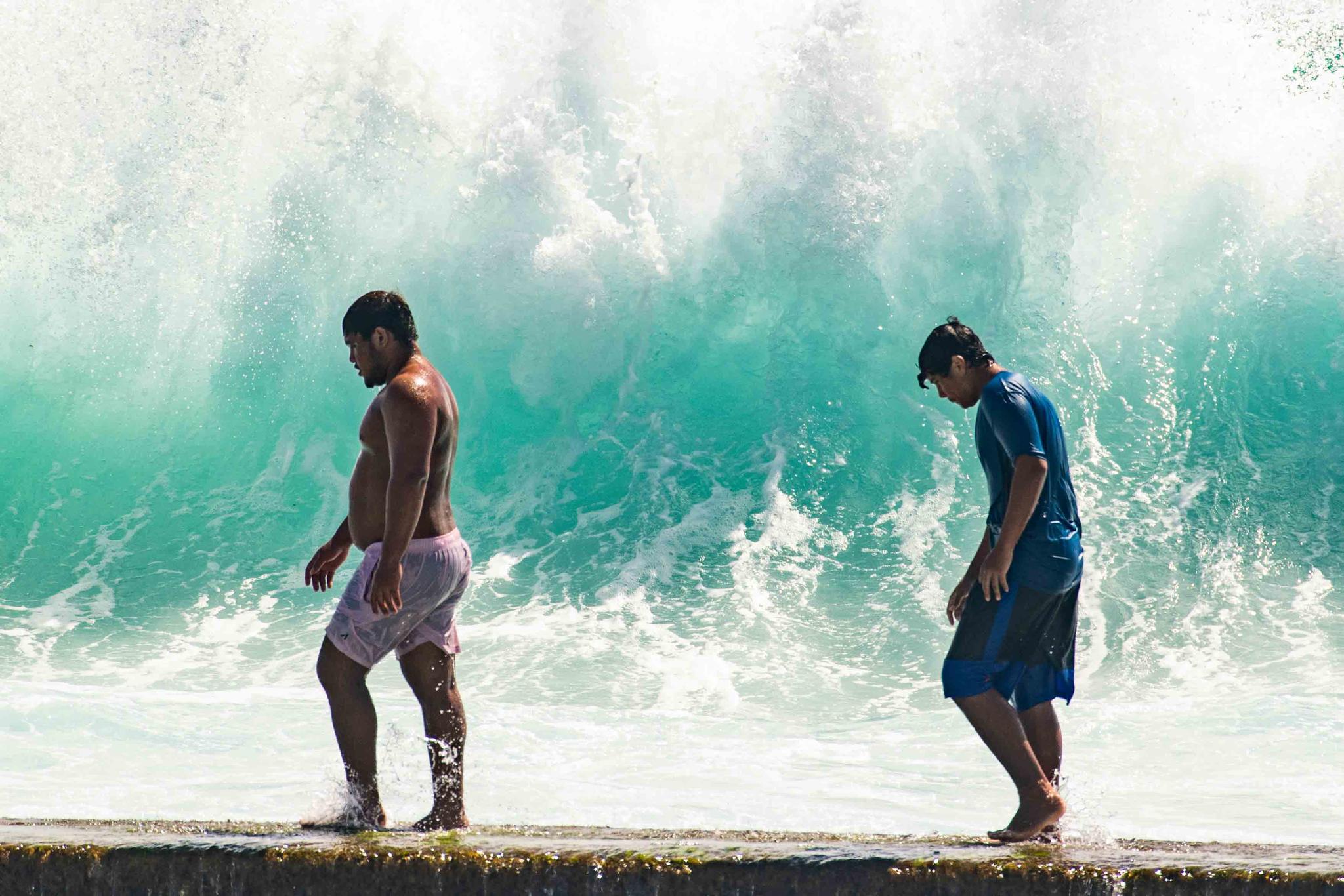 People walk in front of the high surf near Kapahulu Groin (Waikiki Wall) in Waikiki, Hawaii, Sunday, July 17, 2022.