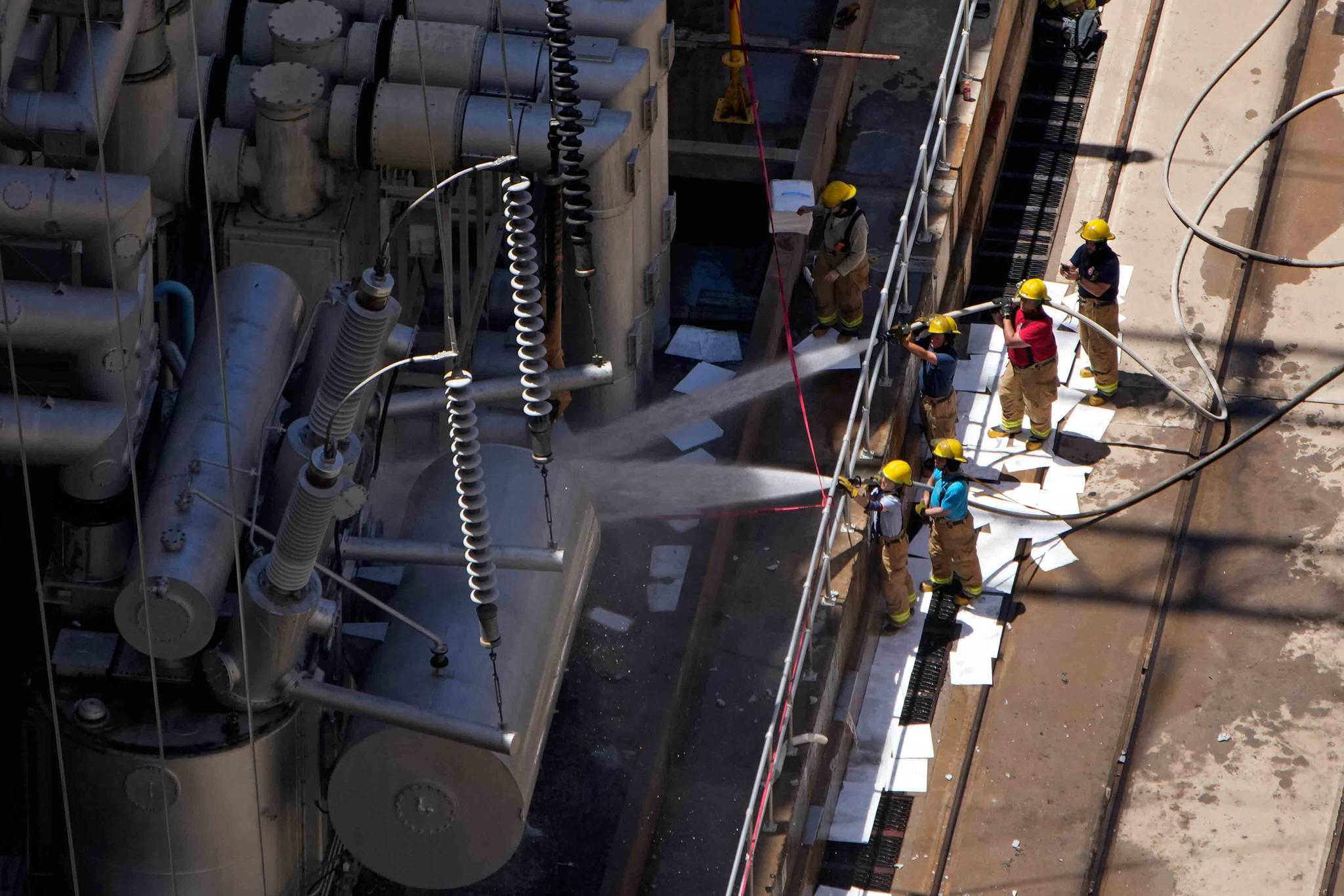 Firefighters spray water after a fire on the Arizona side of the Hoover Dam, Tuesday, July 19, 2022, near Boulder City, Nev. Officials say no one was injured when a transformer at Hoover Dam briefly caught fire Tuesday morning. 