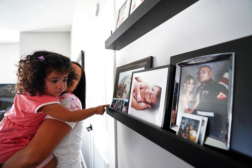 Laura Guerra and her daughter Emilia, 2, look at her father's pictures at their home in Riverside, Calif.