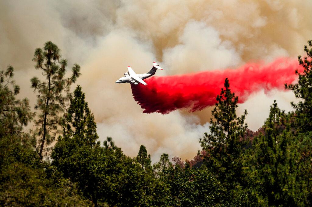 Air tanker drops retardant on fire.