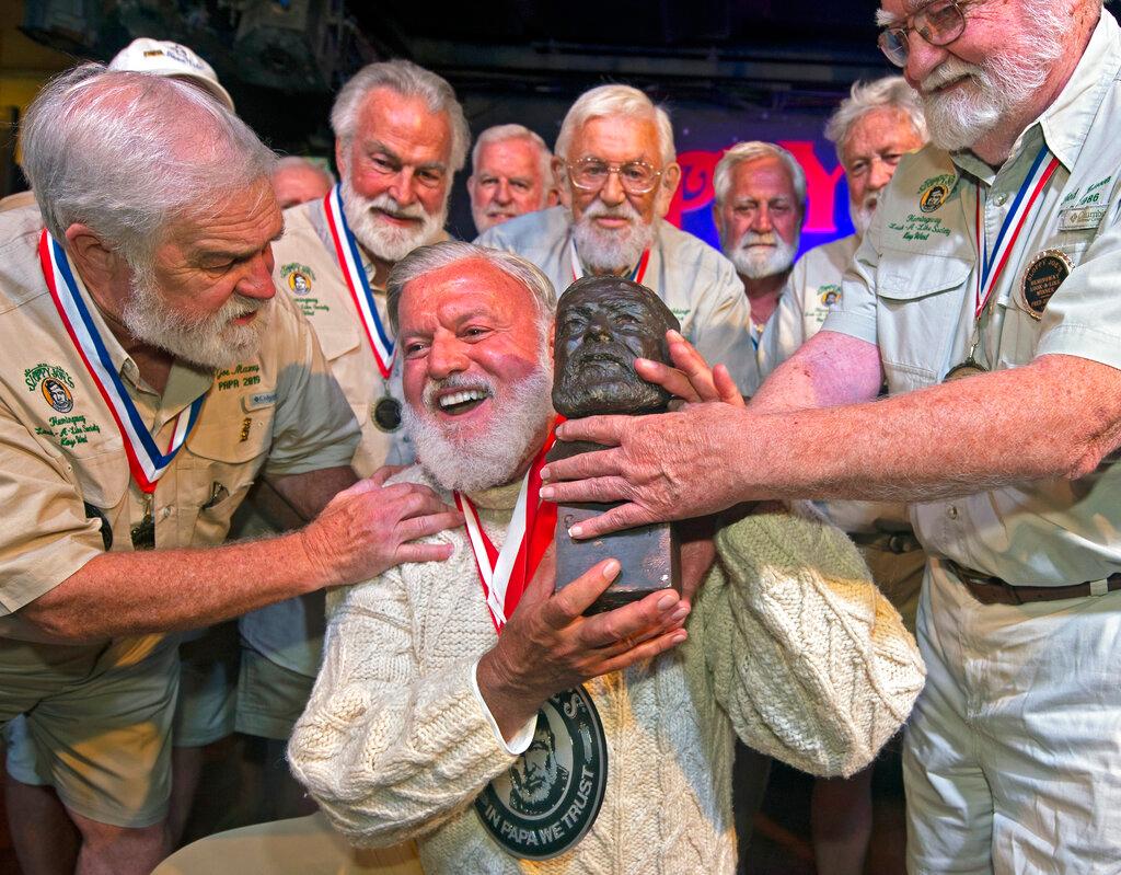 Jon Auvil, center, receives an Ernest Hemingway bust and congratulations after he won the 2022 Hemingway Look-Alike Contest