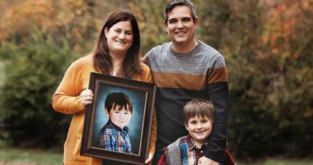 Family of three with their son Ollie in a frame