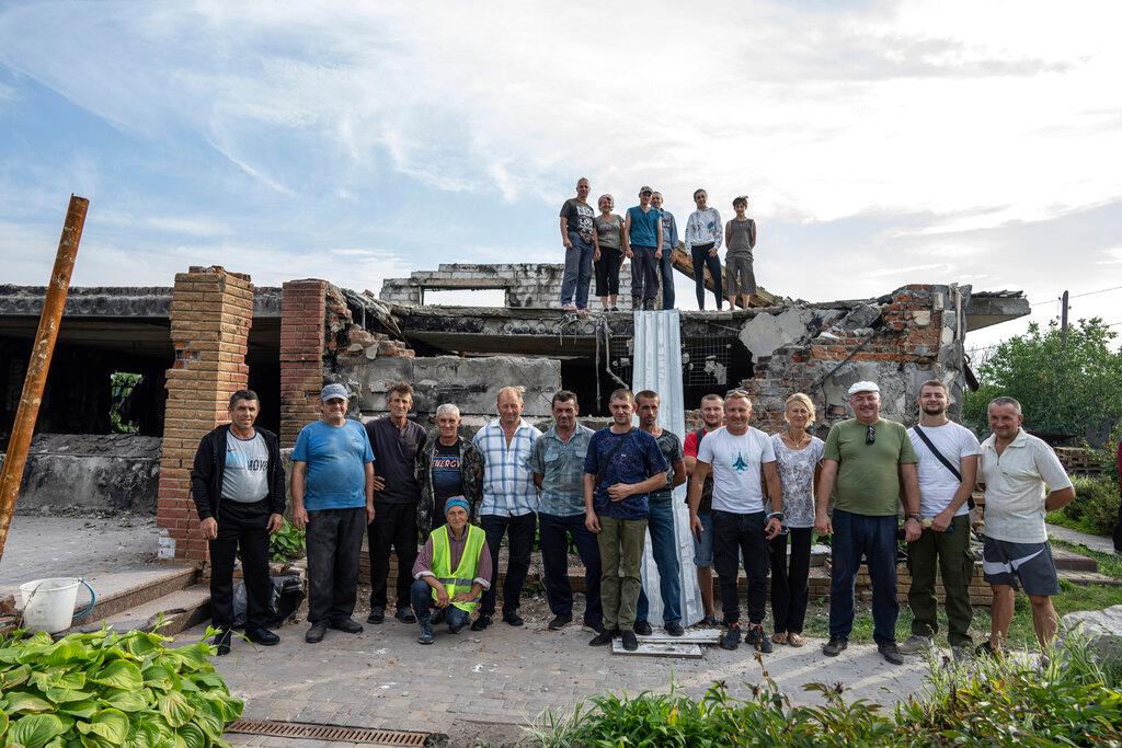 Volunteers pose for a group photo in front of of Zhanna and Serhiy Dynaeva's house which was destroyed by Russian bombardment, in the village of Novoselivka, near Chernihiv, Ukraine