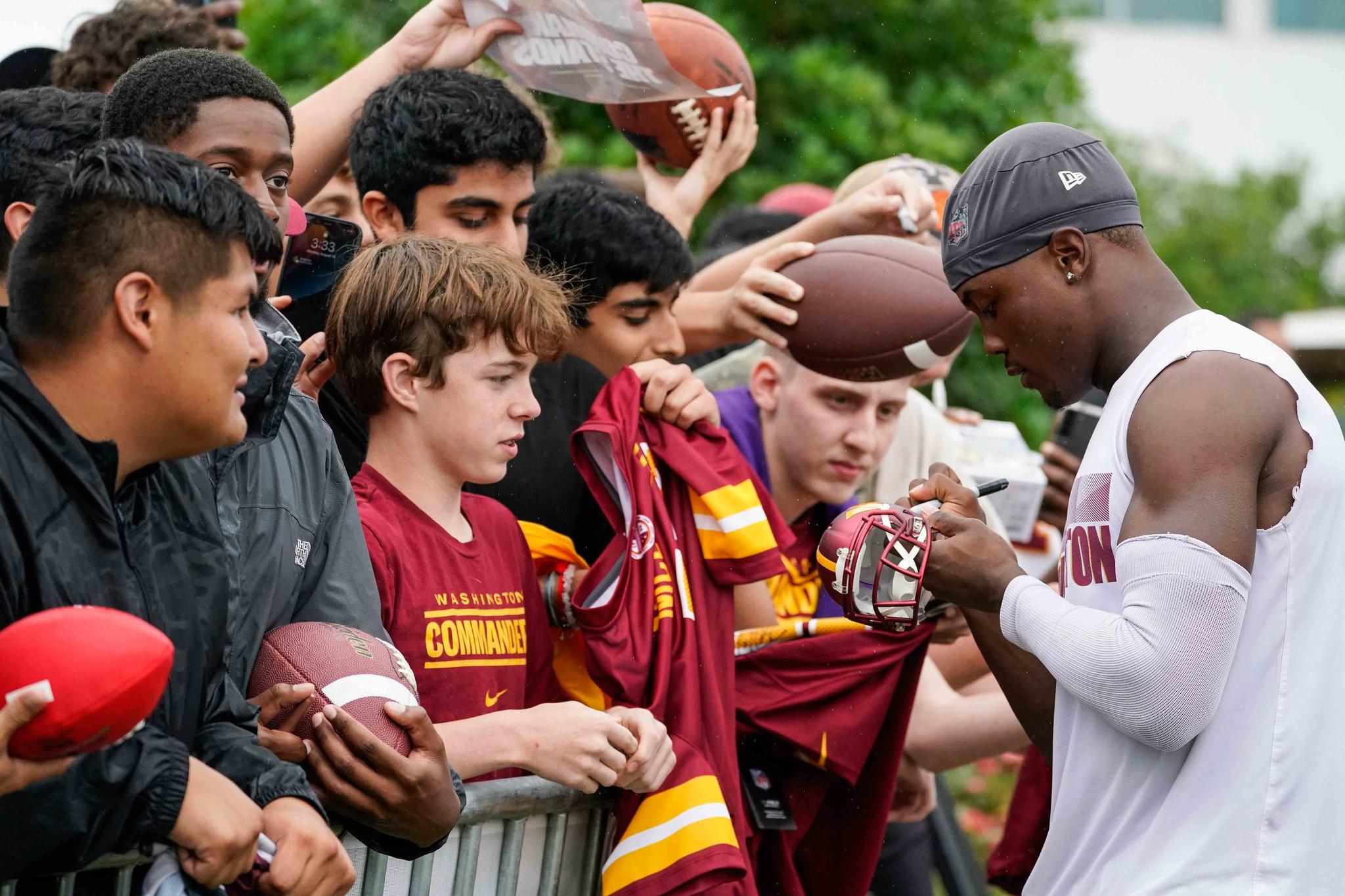 Washington Commanders wide receiver Terry McLaurin, right, signs autographs for fans after practice during NFL football training camp Monday, Aug. 15, 2022, in Ashburn, Va.