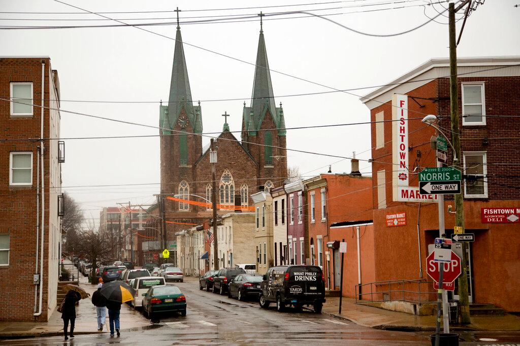 Parked cars and store fronts in neighborhood near church.