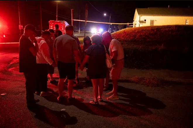 Residents and faculty of the Harbor House Christian Center at 804 Clay Street in Henderson, Ky., gather in prayer after a lone gunman opened fire after an evening prayer service Thursday night, Aug. 25, 2022.