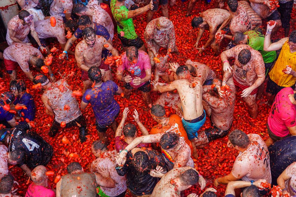 Revellers throw tomatoes at each other during the annual "Tomatina", tomato fight fiesta in the village of Bunol near Valencia, Spain, Wednesday, Aug. 31, 2022. The tomato fight took place once again following a two-year suspension owing to the coronavirus pandemic.