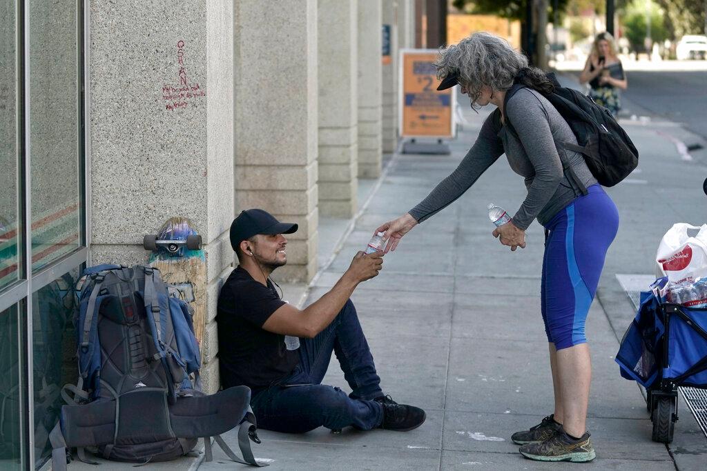 Freddie Ramirez, left, is handed a bottle of water from Kim Burrell, in Sacramento, Calif.
