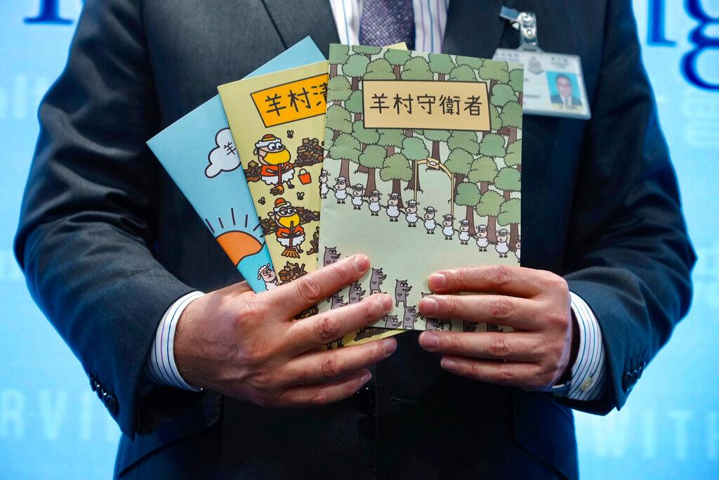  Li Kwai-wah, senior superintendent of Police National Security Department, poses with three children's books that revolve around a village of sheep which has to deal with wolves from a different village 
