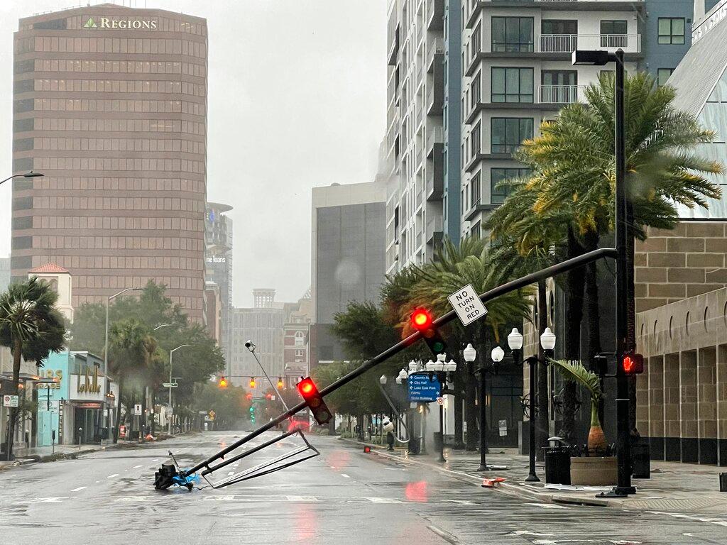 A stoplight pole blown down by Hurricane Ian winds, rests on Orange Avenue in Downtown Orlando, Fla.