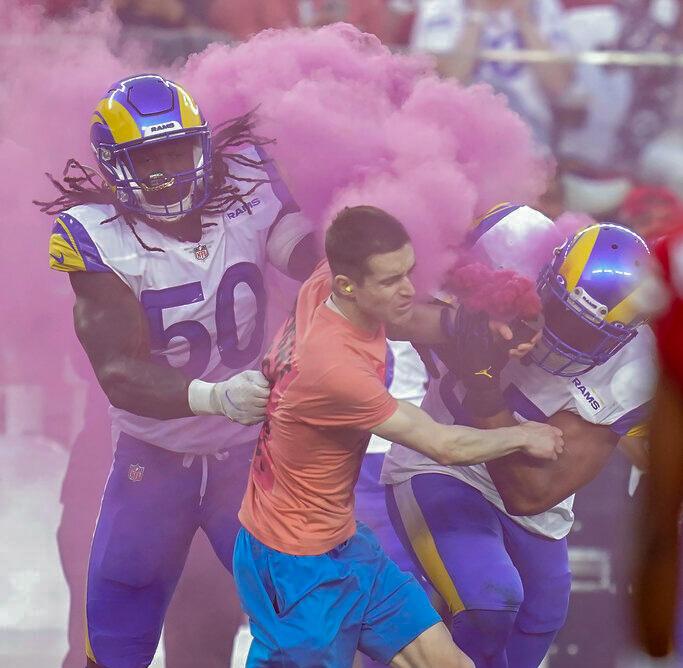 A protester is hit by Los Angeles Rams defensive end Takkarist McKinley (50) and linebacker Bobby Wagner during the first half of an NFL football game between the San Francisco 49ers and the Rams in Santa Clara, Calif.