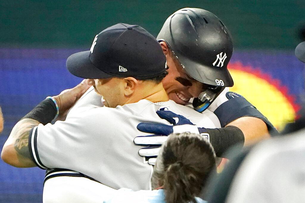 New York Yankees' Aaron Judge, right, hugs teammates after hitting a solo home run, his 62nd of the season, during the first inning in the second baseball game against the Texas Rangers in Arlington, Texas