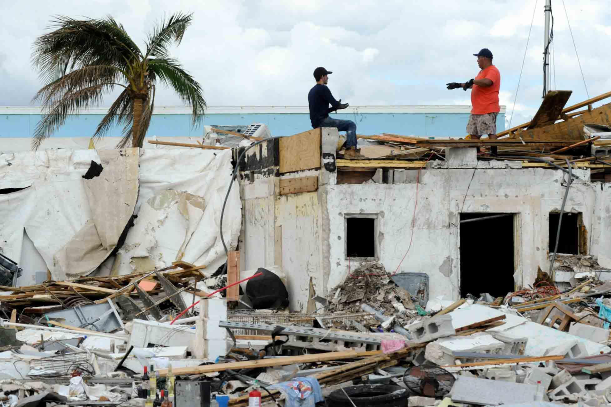 Workers talk atop a building that was heavily damaged by Hurricane Ian at Fort Myers Beach, Fla., on Sunday, Oct. 9, 2022.