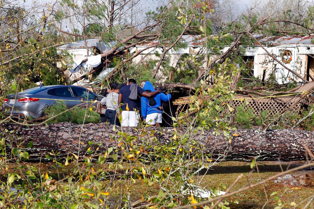 Friends and family pray outside a damaged mobile home, Wednesday, Nov. 30, 2022, in Flatwood, Ala., the day after a severe storm swept through the area. Two people were killed in the Flatwood community just north of the city of Montgomery.