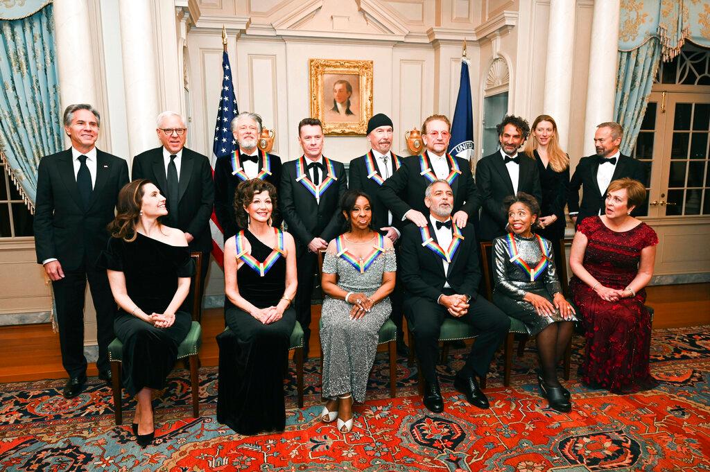 Kennedy Center Honoree Amy Grant, bottom row, 2nd from left, George Clooney, bottom third from right, reacts as he is given a shoulder rub from fellow Honoree Bono during a group photo at the State Department following the Kennedy Center Honors gala dinner, Saturday. Also with Clooney are, front row from left, Evan Ryan, Amy Grant, Gladys Knight, Tania León, Deborah Rutter, back row from left, Antony Blinken, David Rubenstein, Adam Clayton, Larry Mullen Jr., The Edge, Bono, Kennedy Center Honor Producers David Jammy, Liz Kelly and Ian Stewart 