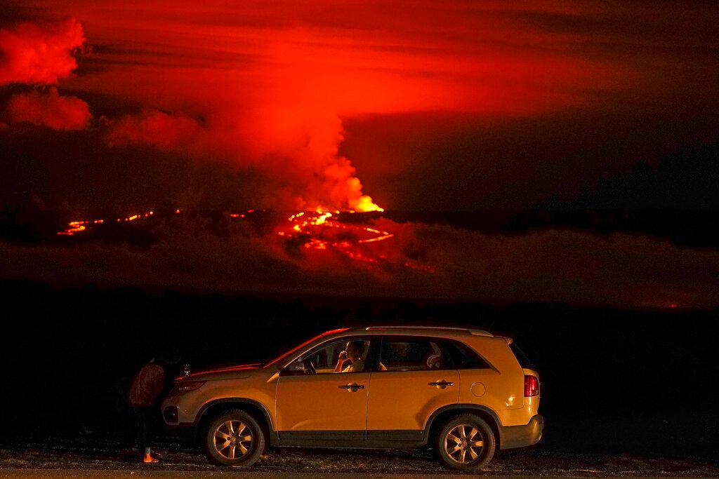 A man talks on a phone in his car alongside Saddle Road as the Mauna Loa volcano erupts. 