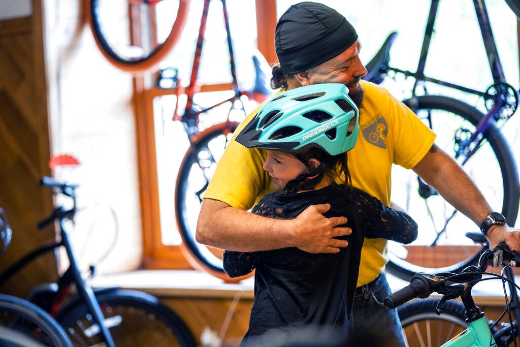 Kadence Horton, 8, of Iron River gives a hug to Steven Pringle, owner of Build a Bicycle - Bicycle Therapy, after he presented her with a new bike at his shop 
