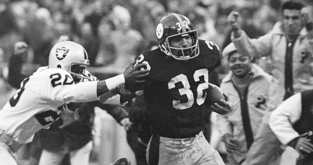 Number 32 football player with ball in hand being grabbed at by #20