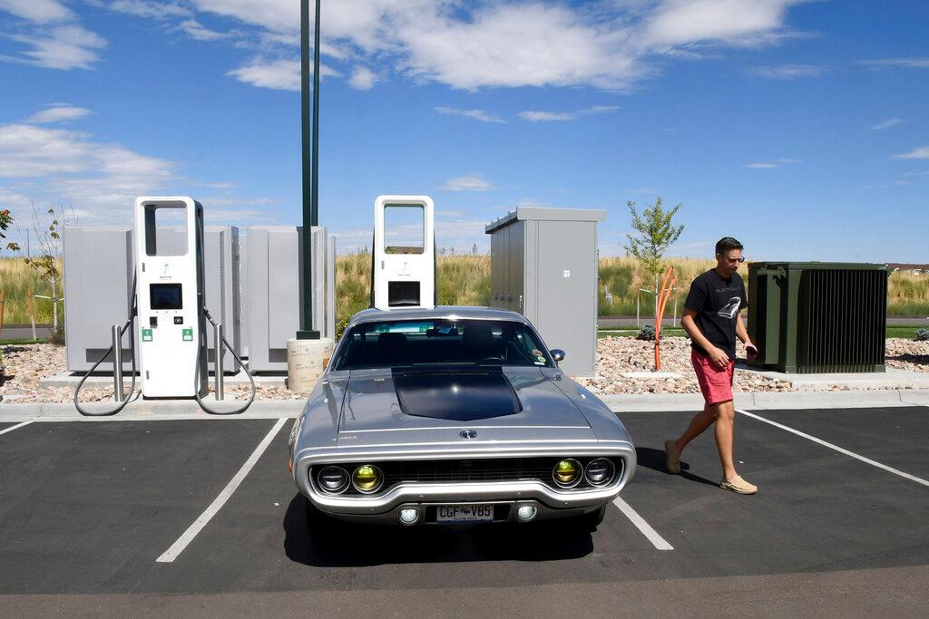 Kevin Erickson walks by his electrified 1972 Plymouth Satellite at a public charging station in Commerce City, Colo.