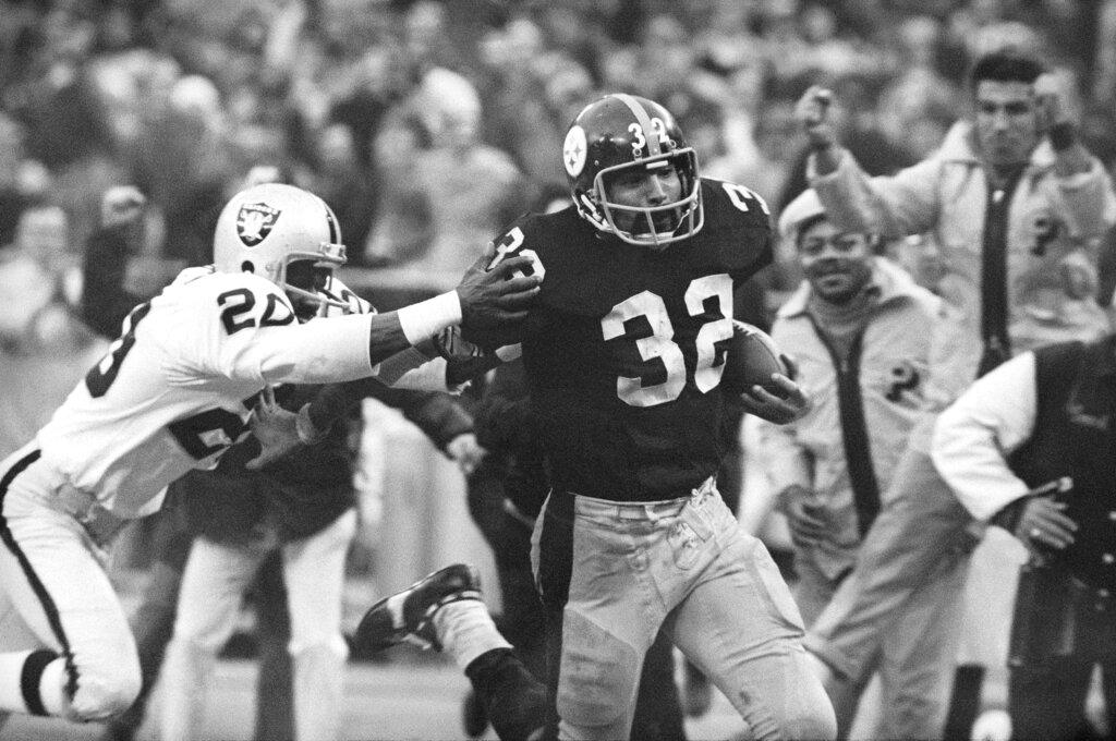 Pittsburgh Steelers' Franco Harris (32) eludes a tackle by Oakland Raiders' Jimmy Warren as he runs 42-yards for a touchdown after catching a deflected pass during an AFC Divisional NFL football playoff game in Pittsburgh, Dec. 23, 1972