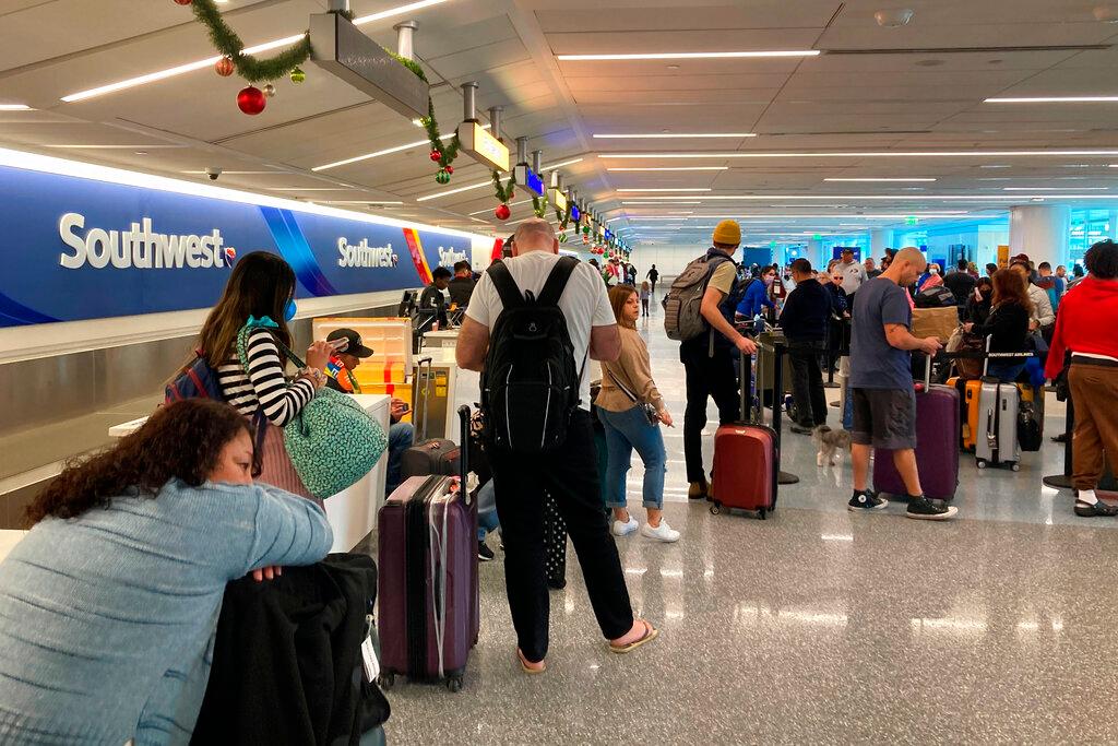 Travelers wait at a Southwest Airlines baggage counter to retrieve their bags