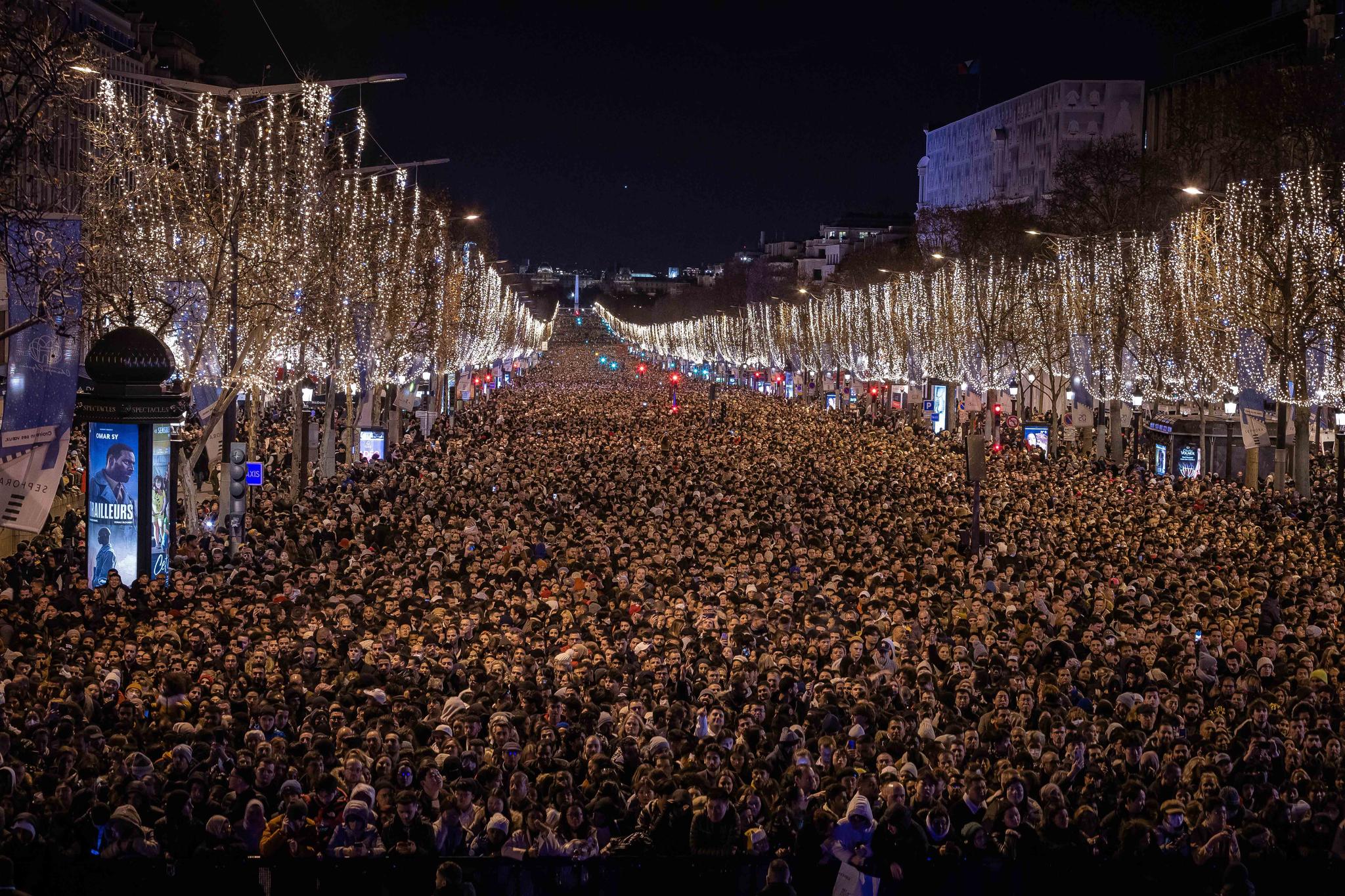 Revelers watch a sound and light show projected on the Arc de Triomphe as they celebrate the New Year on the Champs Elysees, in Paris, France, Saturday, Dec. 31, 2022.