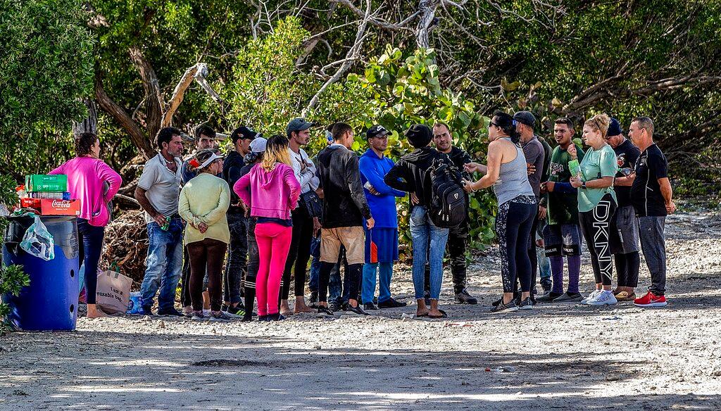 A group of Cuban migrants stand in the sun on the side of U.S. 1 in the Middle Keys island of Duck Key, Fla.