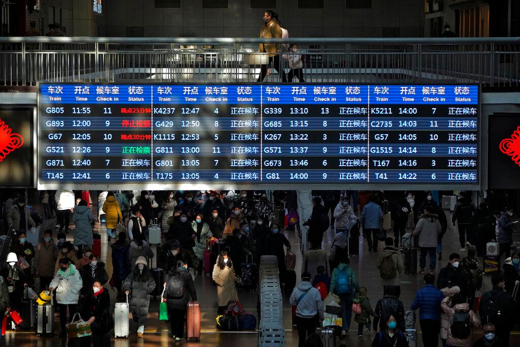 Travelers walk through a trains departure board at the West Railway Station in Beijing, Sunday, Jan. 15, 2023. 