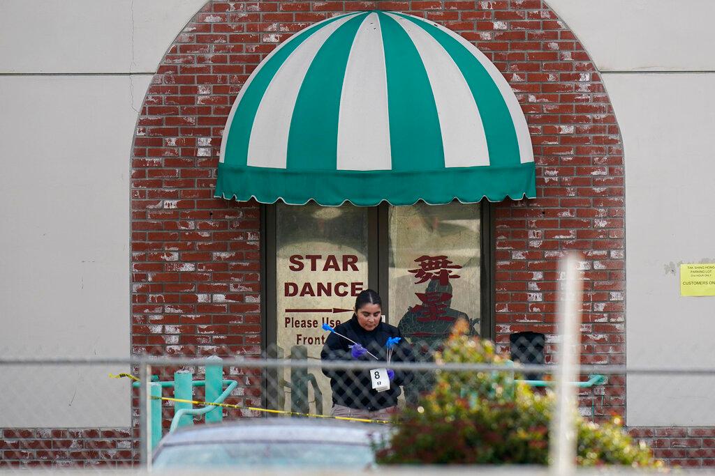 An investigator carries markers outside Star Dance Studio in Monterey Park, Calif.