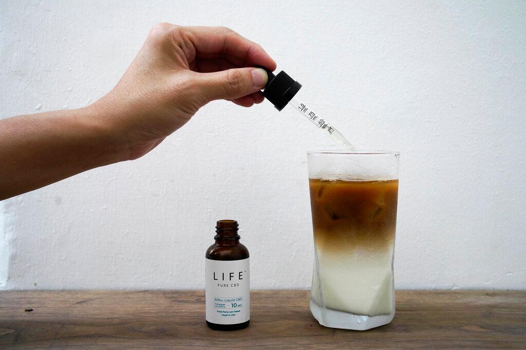 Employee adds drops of water-soluble CBD, or cannabidiol, an essential component of medical marijuana, into a coffee glass at the Found Cafe in Hong Kong 