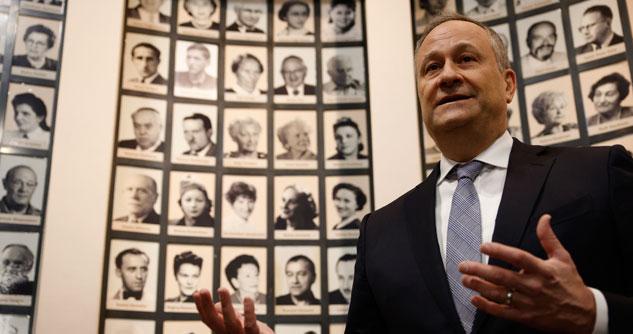 Man in a suit in front of the framed pictures of Auschwitz victims