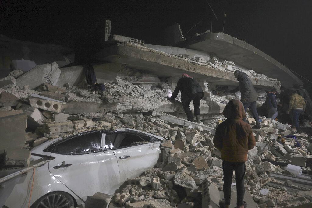 eople and rescue teams try to reach trapped residents inside collapsed buildings.
