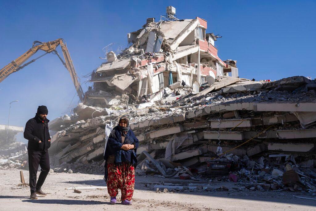 Residents walk in front of a destroyed building in Nurdagi, southeastern Turkey