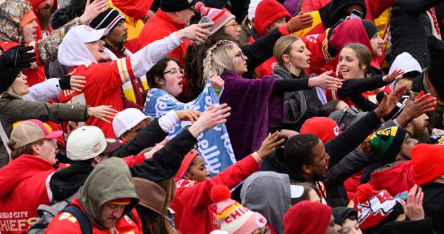 Fans dressed in red and white extending their arms forward for the "tomahawk chop"