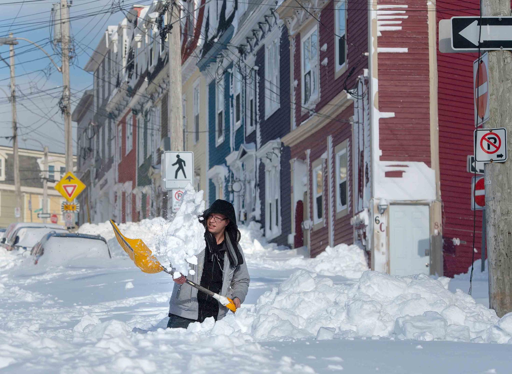 A resident digs a path from his house in St. John's Newfoundland on Saturday