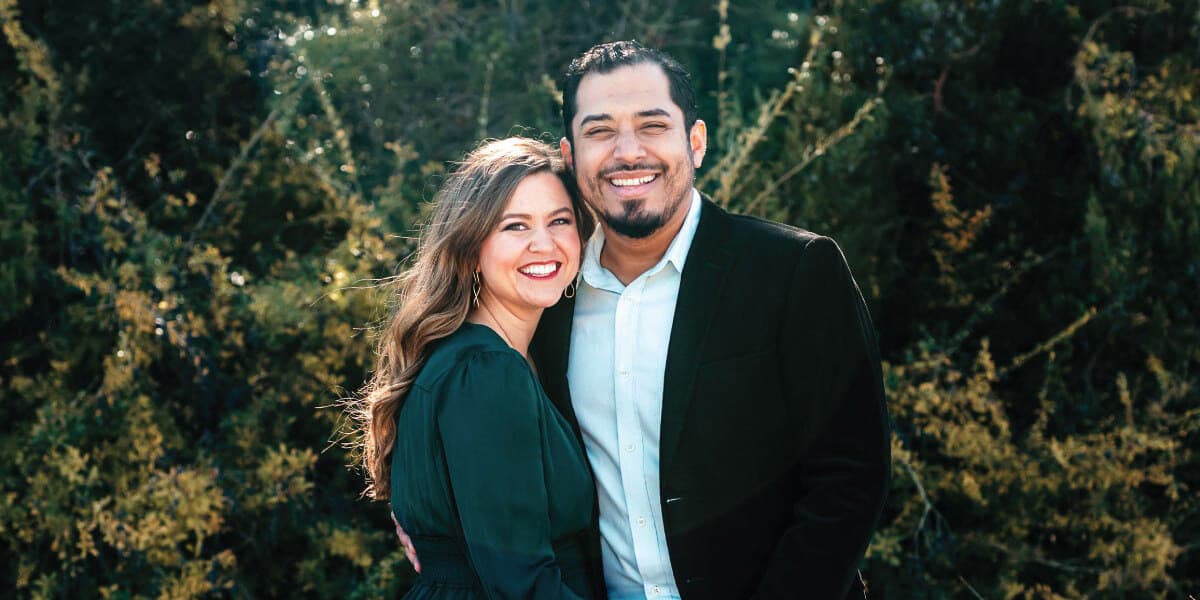 man and women smiling for a photo in front of trees