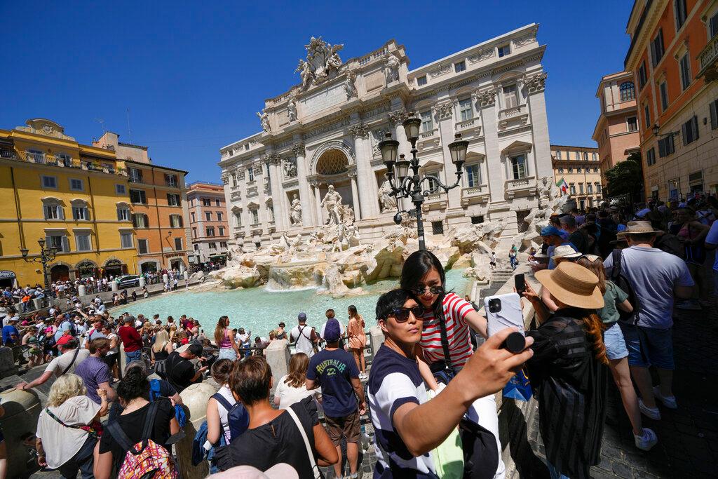 Tourists take a selfie in front of the Trevi Fountain, in Rome.