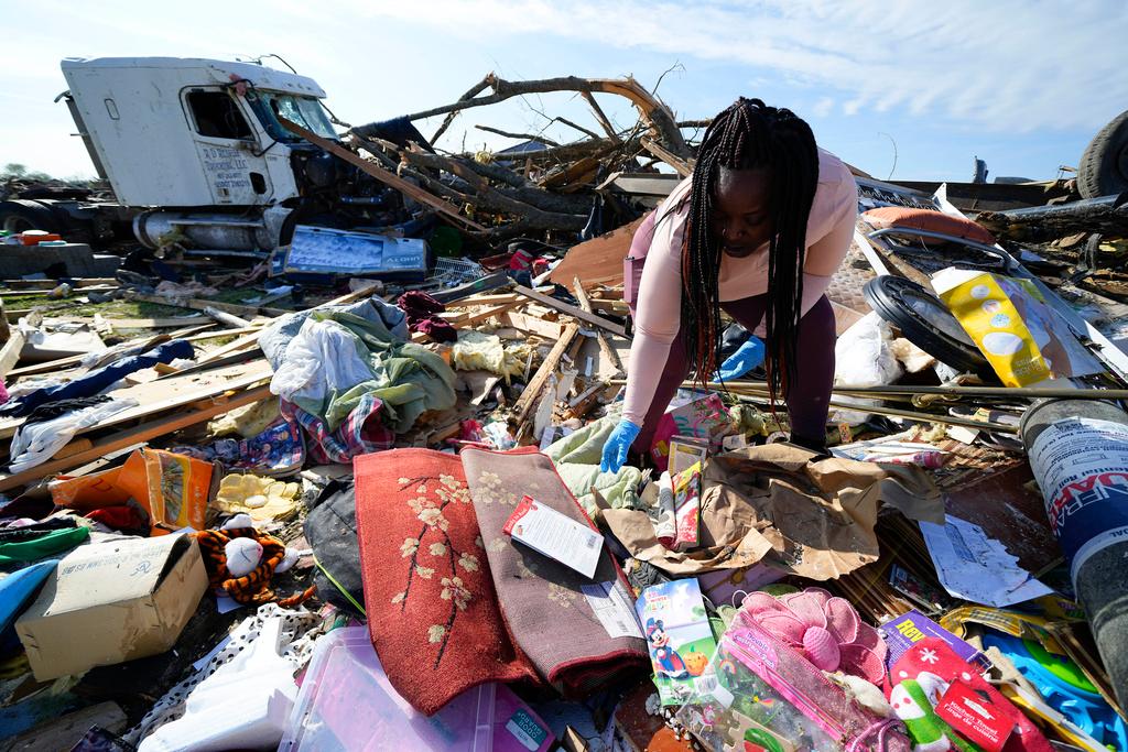 Kimberly Patton surveys through the belongings at the spot of a family member's home after a tornado 