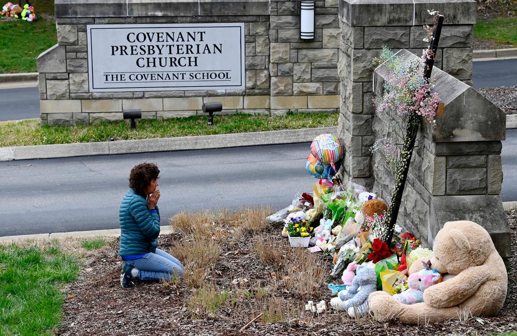 Robin Wolfeden prays in front of a makeshift memorial at the entrance to The Covenant School 