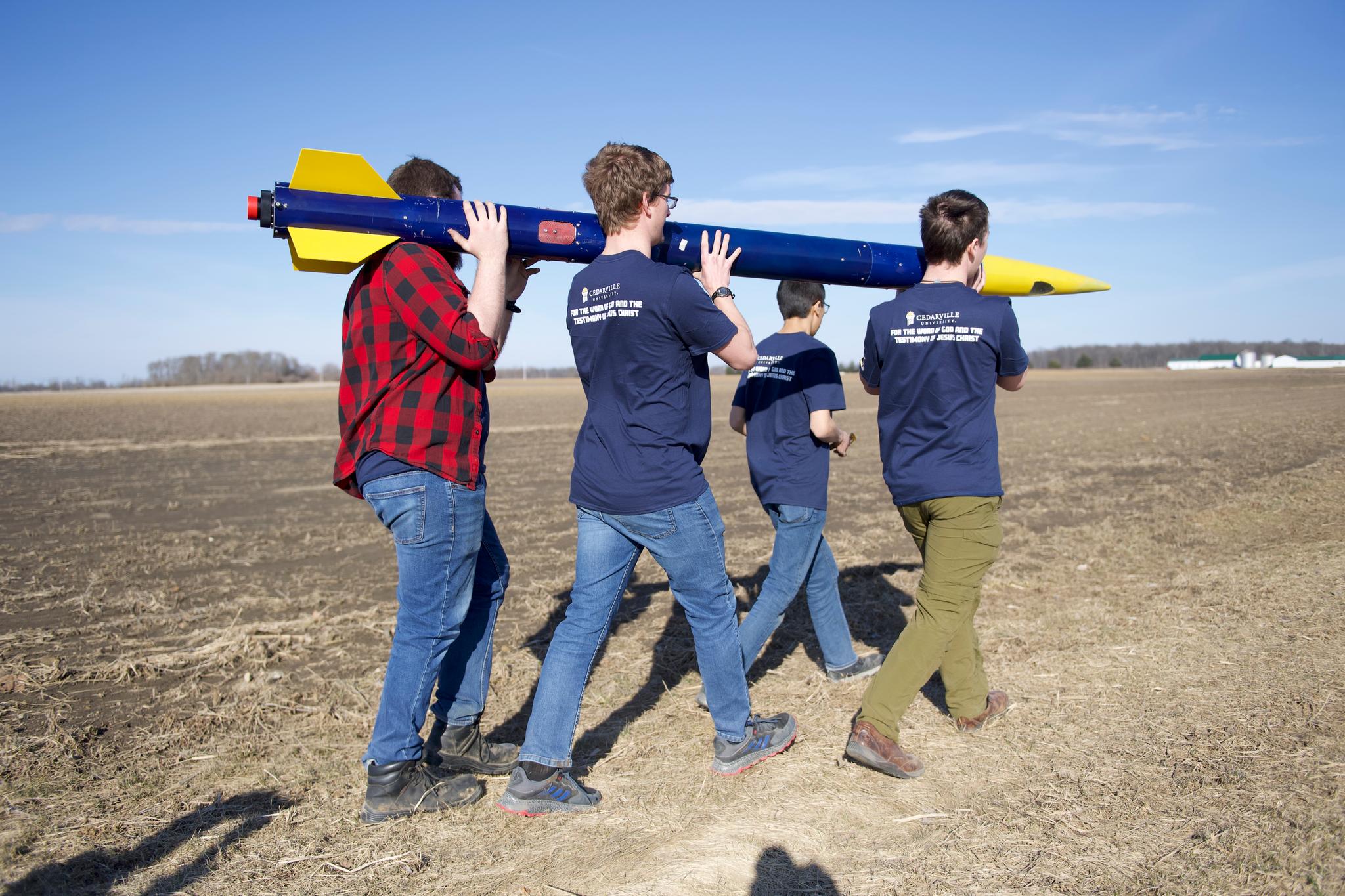 Last year’s senior design students carry their rocket out to its launch site