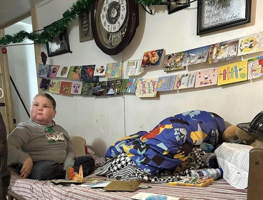 Andrew Miller sitting on his bed with some birthday cards for his ninth birthday. 