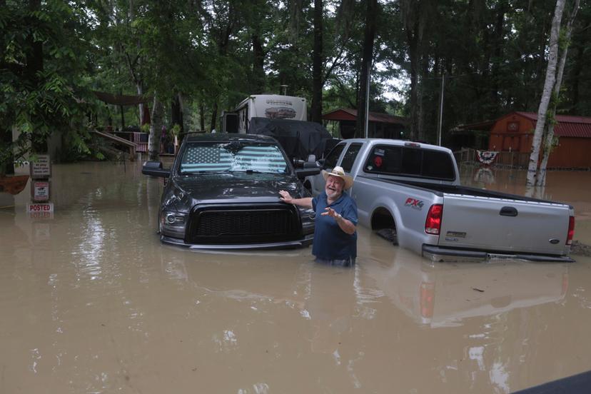 A man waves at Texas Parks & Wildlife Department game wardens as they arrive by boat to rescue residents from floodwaters in Liberty County, Texas