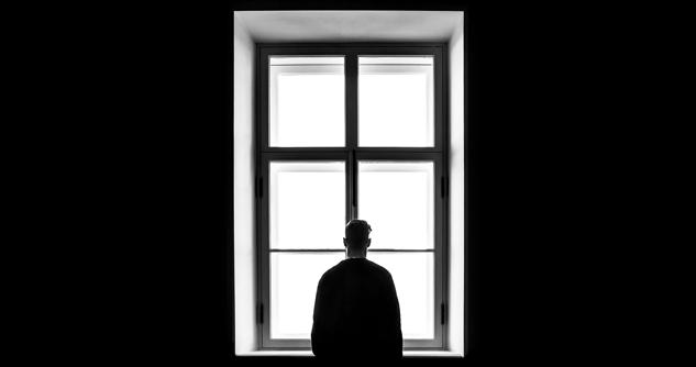 black and white photo of man looking out window